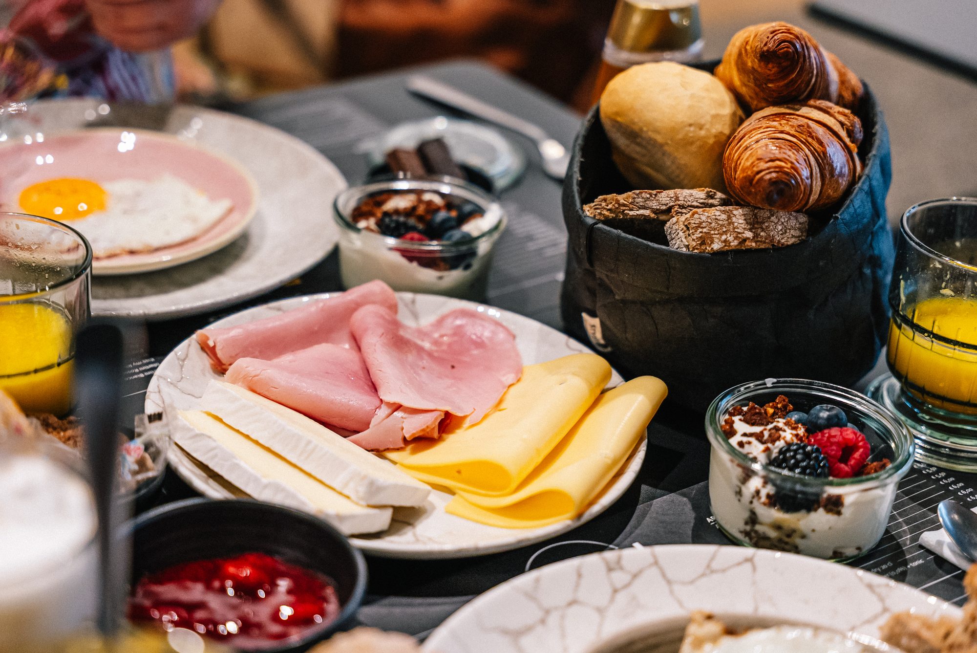 A Juliette breakfast table — eggs, ham & cheese, croissants, granola.